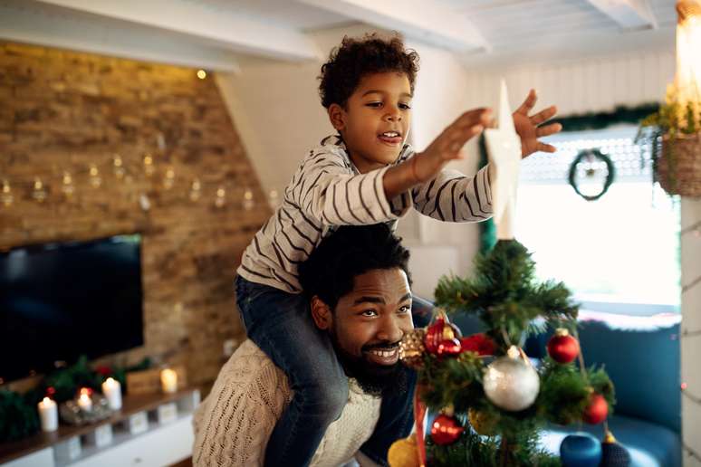 Imagem meramente ilustra mostra pai e filho decorando árvore de natal