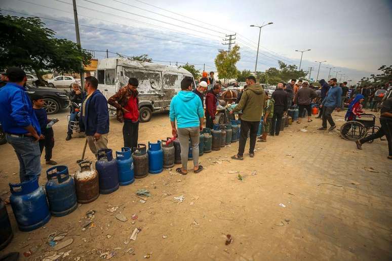Palestinos fazem fila em frente a um posto de gasolina para abastecer seus cilindros de cozinha após a chegada de 150 caminhões com suprimentos de ajuda à Faixa de Gaza pela primeira vez em 49 dias, como parte do início da pausa humanitária de 4 dias para troca de prisioneiros entre o exército israelense e o grupo palestino Hamas em Khan Yunis, Gaza