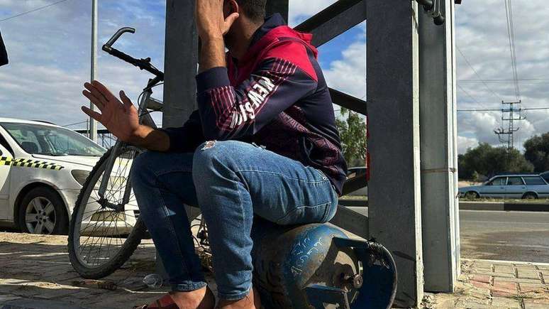 Um jovem sentado sobre um cilindro de gás de cozinha em Deir al-Balah
