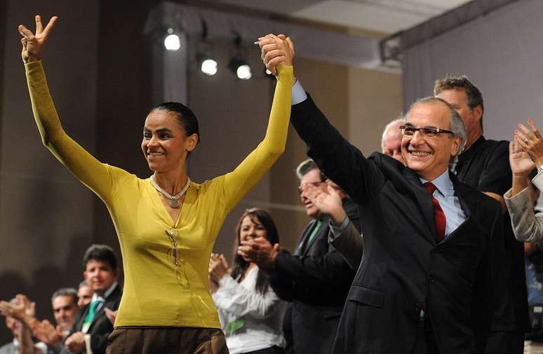 Foto tirada em 2010 mostra a então candidata à Presidência pelo PV, Marina Silva, de mãos levantadas junto com o seu candidato a vice, o empresário Guilherme Leal, cofundador da Natura, em evento de campanha em que ambos são aplaudidos por correligionários