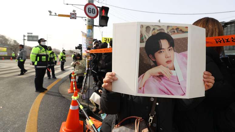 Fã de Jin, membro do BTS, segura sua foto em frente a um campo de treinamento do Exército na Coreia do Sul, em dezembro de 2022