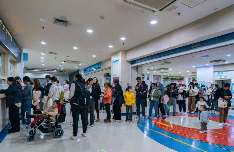 Pais de filhos que sofrem de doenças respiratórias fazem fila em um hospital infantil em Chongqing