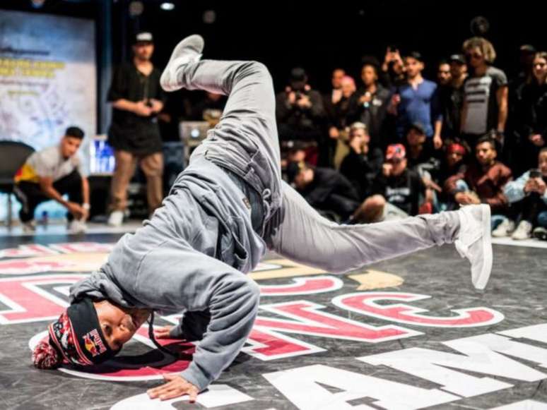 Imagem mostra um jovem negro no chão em competição de break dance