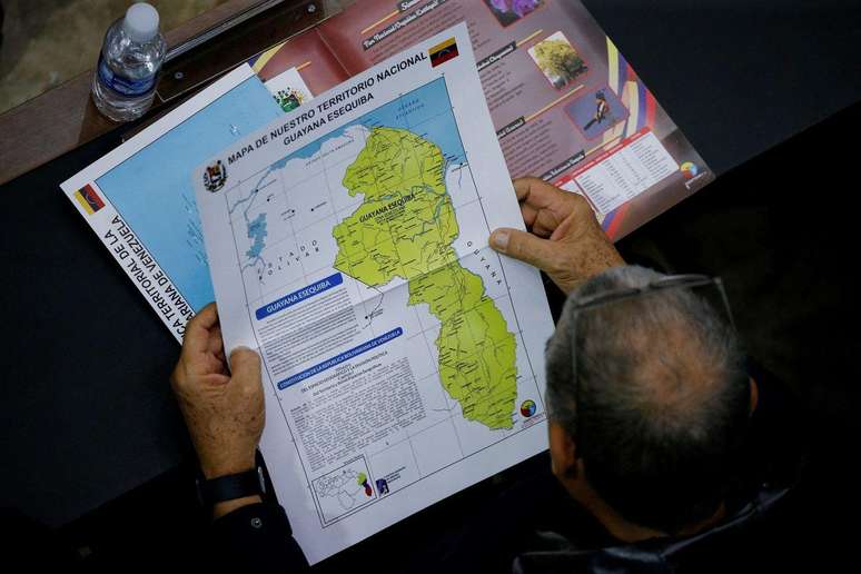 Um membro da Assembleia Nacional da Venezuela segura um mapa que mostra a disputada região de Essequibo como parte do país