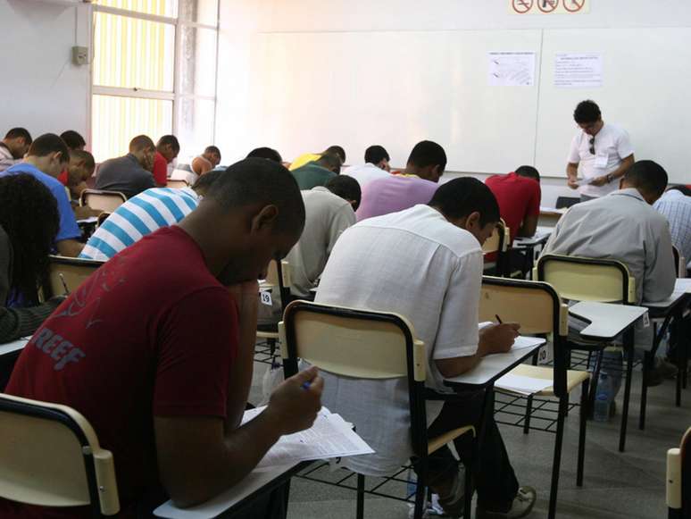 A imagem mostra pessoas negras, dentro de uma sala de aula, realizando uma prova. Essa é uma representação de negros prestando concursos públicos.