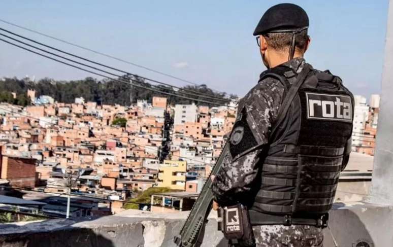 Imagem mostra policial da Rota de costas e segurando uma arma.