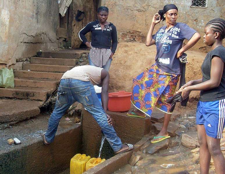 Pessoas em Yaoundé pegando água de uma fonte