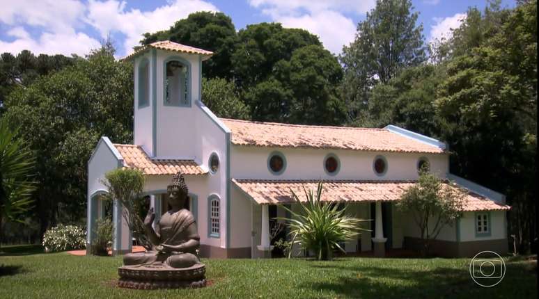 O pequeno santuário possui torre com sino e um grande Buda perto da entrada, simbolizando a diversidade de fé da apresentadora