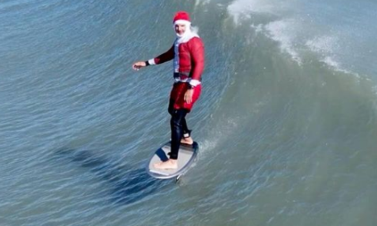 Surfista fantasiado de Papai Noel em praia dos EUA