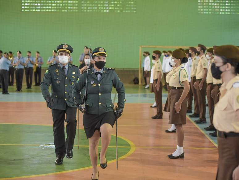 A imagem mostra alunos de um colégio militar junto de profissionais da instituição