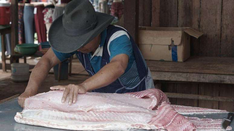 Trabalhador limpa e corta pedaços de pirarucu para venda no mercado de Riberalta