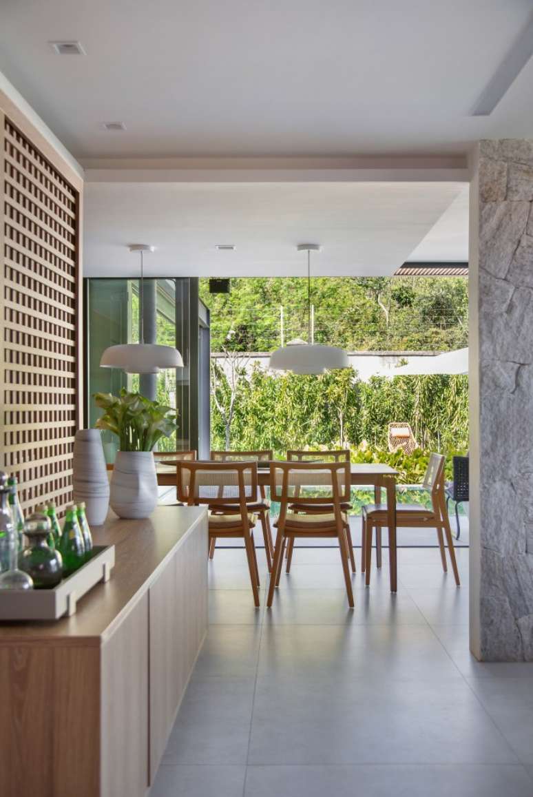 Casa de 300 m&sup2; tem cozinha verde oliva e &aacute;rea gourmet em cont&ecirc;iner. Projeto de Lana Rocha. Na foto, sala de jantar com grandes janelas para jardim.