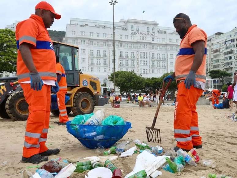 Imagem mostra dois garis negros trabalhando para retirar o lixo produzido durante as festas de fim de ano no Rio de Janeiro.