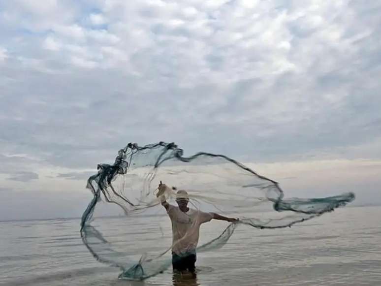 A imagem mostra um homem quilombola, no mar, pescando