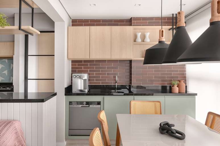 Apê de 84 m² ganha décor delicado em tons de azul, verde e rosa. Projeto de Dani Espírito Santo. Na foto, varanda gourmet com parede com ceramica que imita tijolinho, mesa e marcenaria verde.
