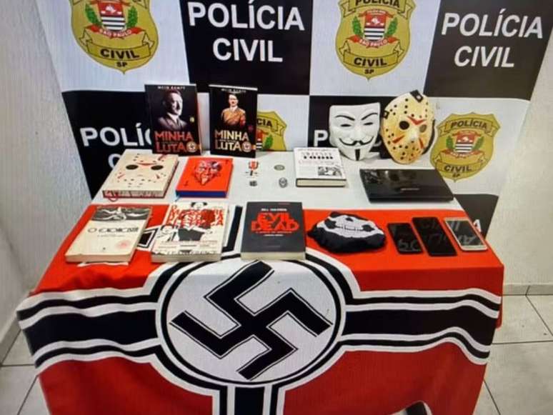 Imagem mostra uma mesa com objetos encontrados na casa do suspeito de nazismo