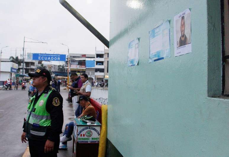 Um policial peruano na fronteira com o Equador ao lado de uma foto de José Adolfo Macias, conhecido como 'Fito'