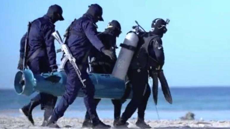Quatro membros da Al-Qassam carregam o torpedo 'Al Asef' para o mar em v&iacute;deo