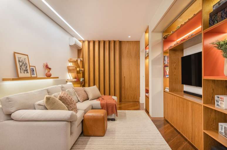 Project by Fernanda Dabbur. In the photo, a living room with a carpentry bookcase with illuminated niches and space for the TV. Lightweight sofa with leather pouf and light beige carpet. Project by Fernanda Dabbur. In the photo, a living room with a carpentry bookcase with illuminated niches and space for the TV. Lightweight sofa with leather pouf and light beige carpet.