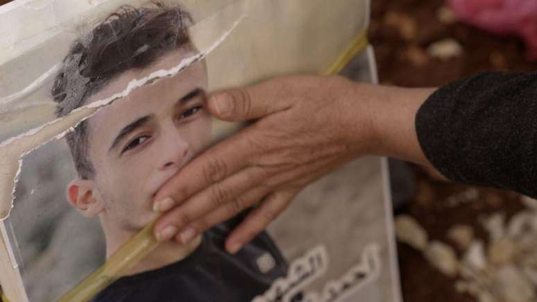 Hand of the mother of the four brothers pictured next to the grave of one of her children