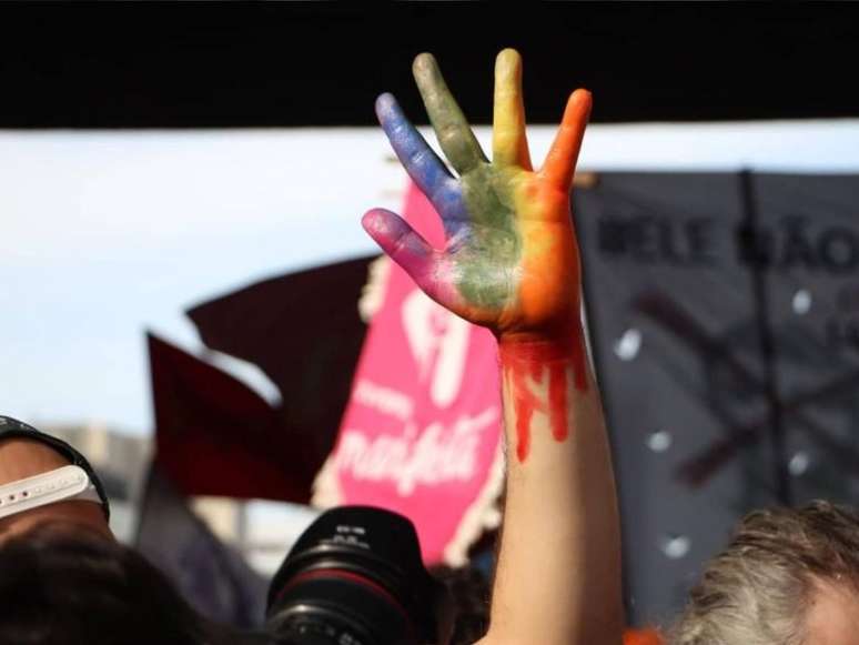 Imagem mostra uma mão pintada com as cores da bandeira LGBTQIA+.