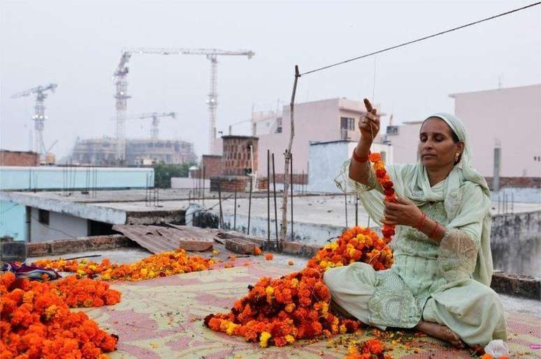 Shakila Bano faz uma guirlanda de flores de calêndula em sua casa: a economia do templo de Ayodhya depende de parte dos muçulmanos