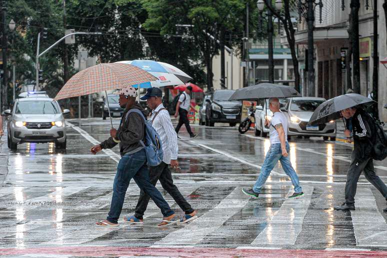 Pedestres enfrentam chuva forte na região central da cidade de São Paulo na tarde deste domingo, 21 de janeiro de 2024