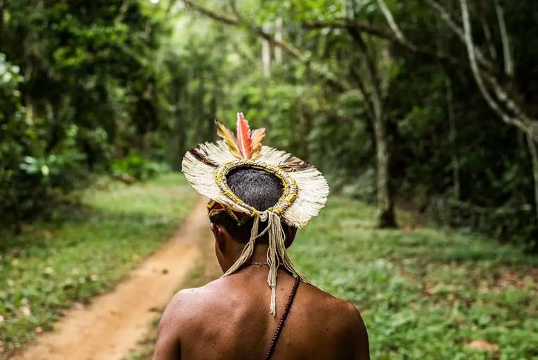 Imagem mostra homem indígena de costas caminhando em Aldeia Pataxó.