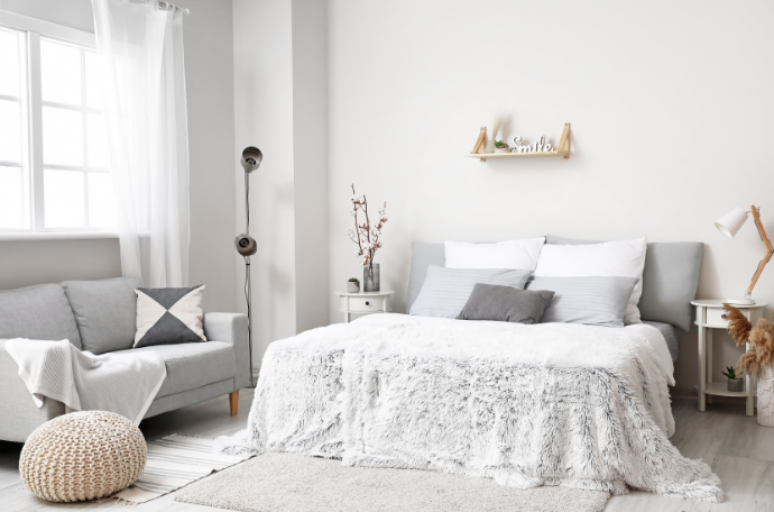 8. Sofá para quarto: ambiente moderno e aconchegante com sofá cinza, cama confortável e decoração minimalista em tons neutros – Foto: Shutterstock