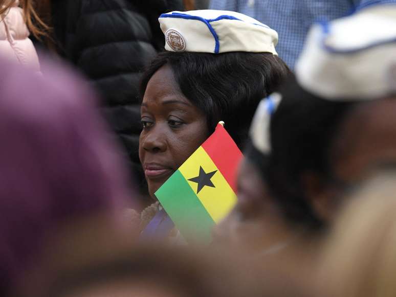 A imagem mostra uma mulher negra retinta segura a bandeira de Gana, país africano, em uma audiência geral no Vaticano em 28 de março de 2018.