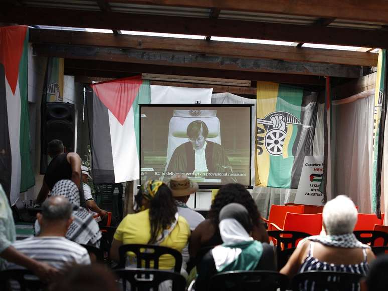 A imagem mostra um grupo de pessoas reunidas para assistir a decisão do Tribunal Internacional de Justiça sobre a ação movida pela África do Sul contra Israel em 26 de janeiro de 2024.