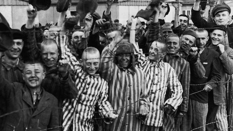 Prisioneiros do campo de concentração de Dachau comemorando a libertação por soldados americanos; muitos soldados descreveram as cenas horríveis que testemunharam ao entrar nesses locais