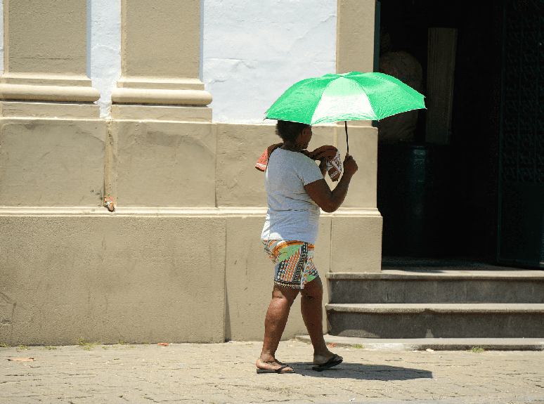 Mulher negra andando na rua durante forte onda de calor no Rio de Janeiro.