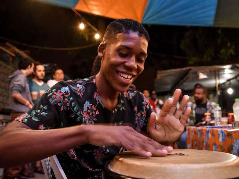 A imagem mostra um músico negro durante uma roda de samba do Poeira Pura.