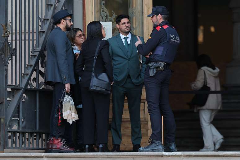 Lucia Alves (2º-L), mãe do futebolista brasileiro Dani Alves, fala com um agente da polícia ao chegar para o julgamento com a advogada da família, Graziele Queiroz (C), no Supremo Tribunal de Justiça da Catalunha, em Barcelona, a 5 de fevereiro de 2024