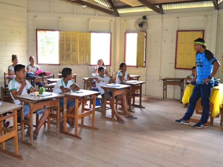 A imagem mostra uma sala de aula com professor e alunos indígenas. O Ministério Público Federal e o Ministério Público do Pará recomendam a estruturação de escolas em Jacareacanga com o objetivo de valorizar a cultura materna.