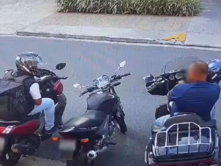 A imagem mostra o policial civil em sua moto e o assaltante, de capacete, ao seu lado, anunciando assalto.