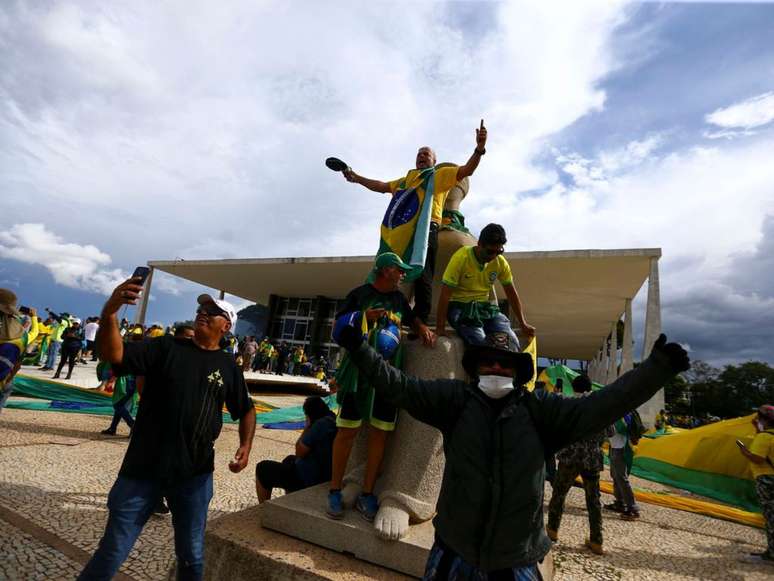 A imagem mostra homens comemorando a invasão ao Congresso Nacional, em Brasília, em janeiro de 2023.