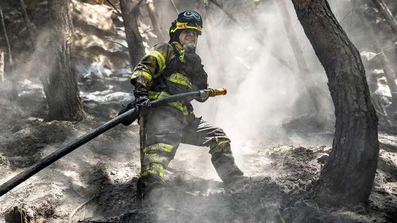 Imagem de bombeiro apagando fogo em floresta