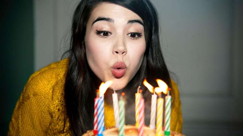 Uma jovem sopra as velas em bolo