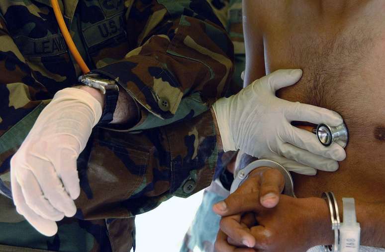 Os prisioneiros passavam por exames médicos ao chegar à base. Muitos deles estavam desnutridos e sofriam de doenças diversas. Na foto, o primeiro tenente Edwin Leavitt ouve o coração de um detido