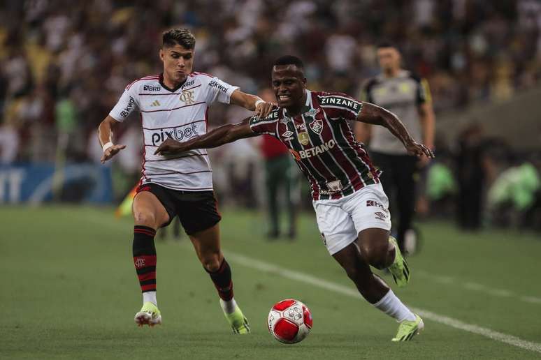 Luiz Araújo e Jhon Arias disputando a bola. Jhon está pendendo o corpo, em sinal de proteção a bola.