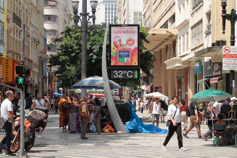 Pedestres se protegem do calor na região central da cidade de São Paulo