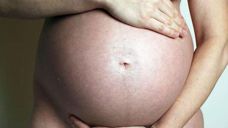 Mulher grávida colocando as mãos em volta da barriga