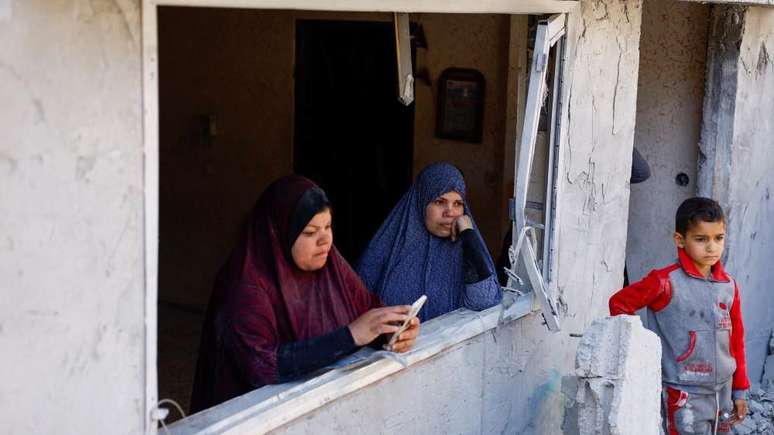 Palestinos olham destruição por janela de casa