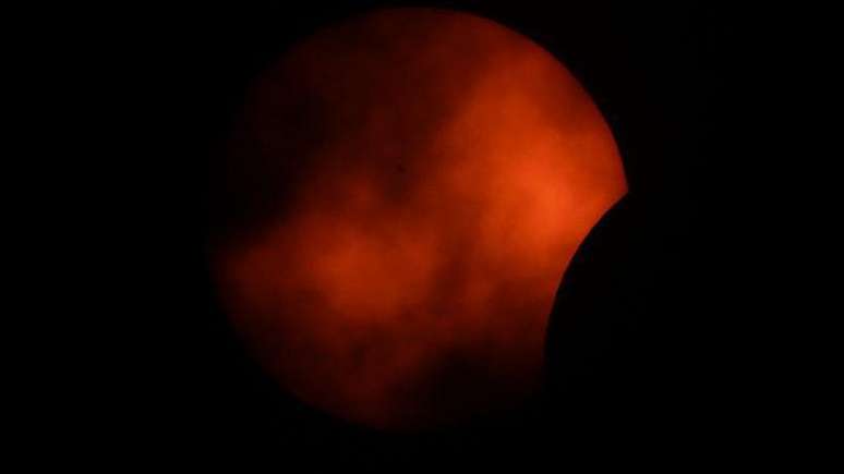 Nuvens passam em frente ao sol na fase inicial de um eclipse solar total visto em Arlington, Texas, nos EUA