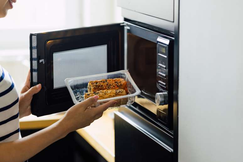 Mulher fazendo uma refeição em um forno de micro-ondas