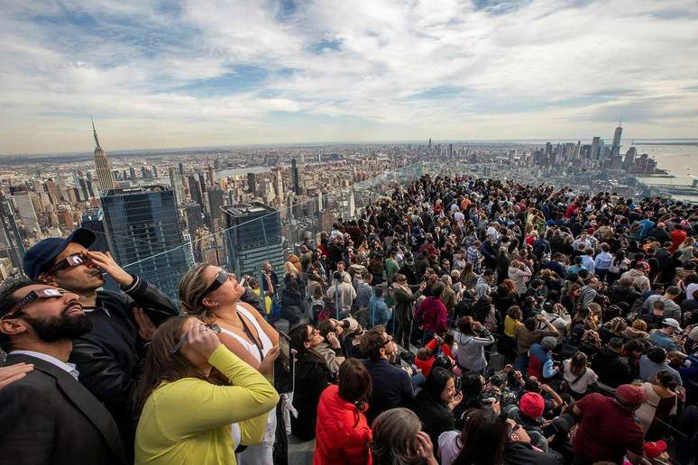 Multidão observando o eclipse com óculos de proteção