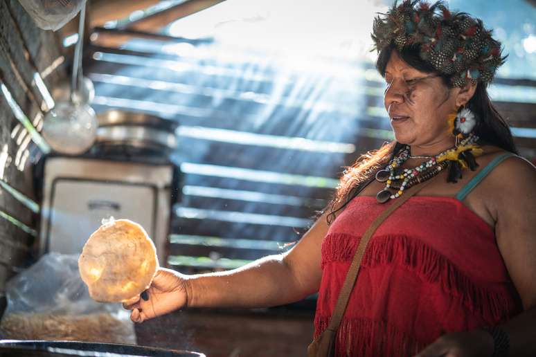 Indígena cozinhando comida típica da culinária cotiadiana dela.