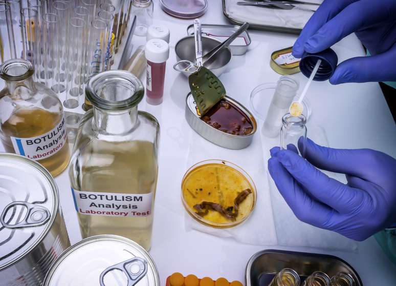 Cientista analisa uma amostra de uma lata de alimentos enlatados, um dos causadores de infecção por botulismo